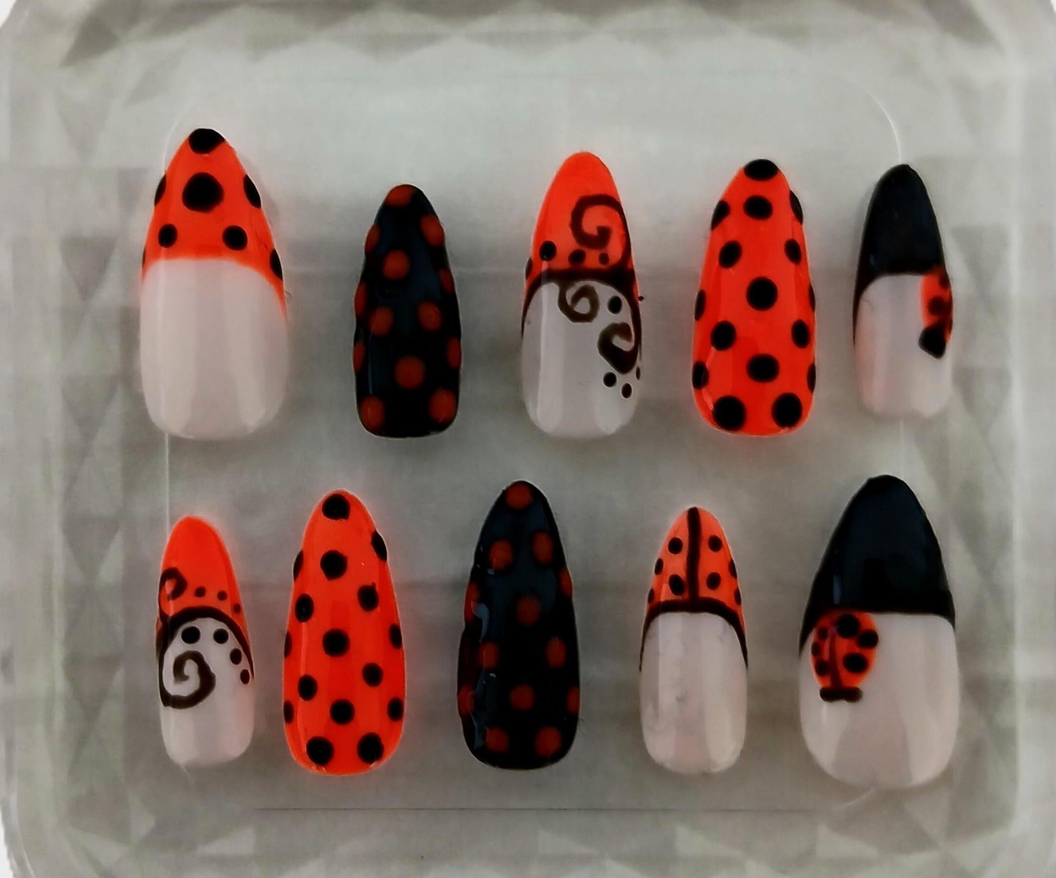Set of decorative false nails with black, red, and white patterns on a clear background