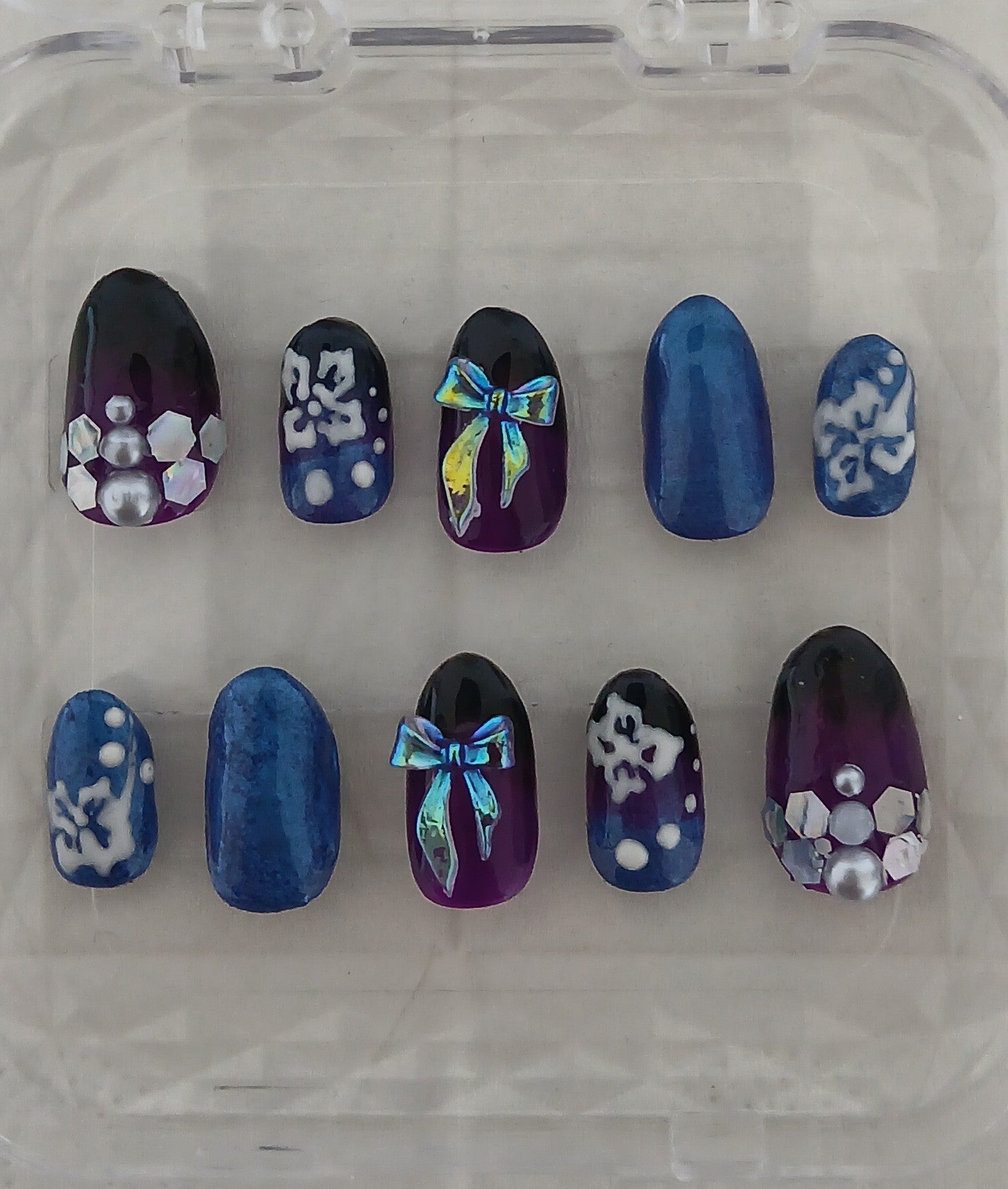 Set of decorative nails with blue, purple, and white designs on a clear background