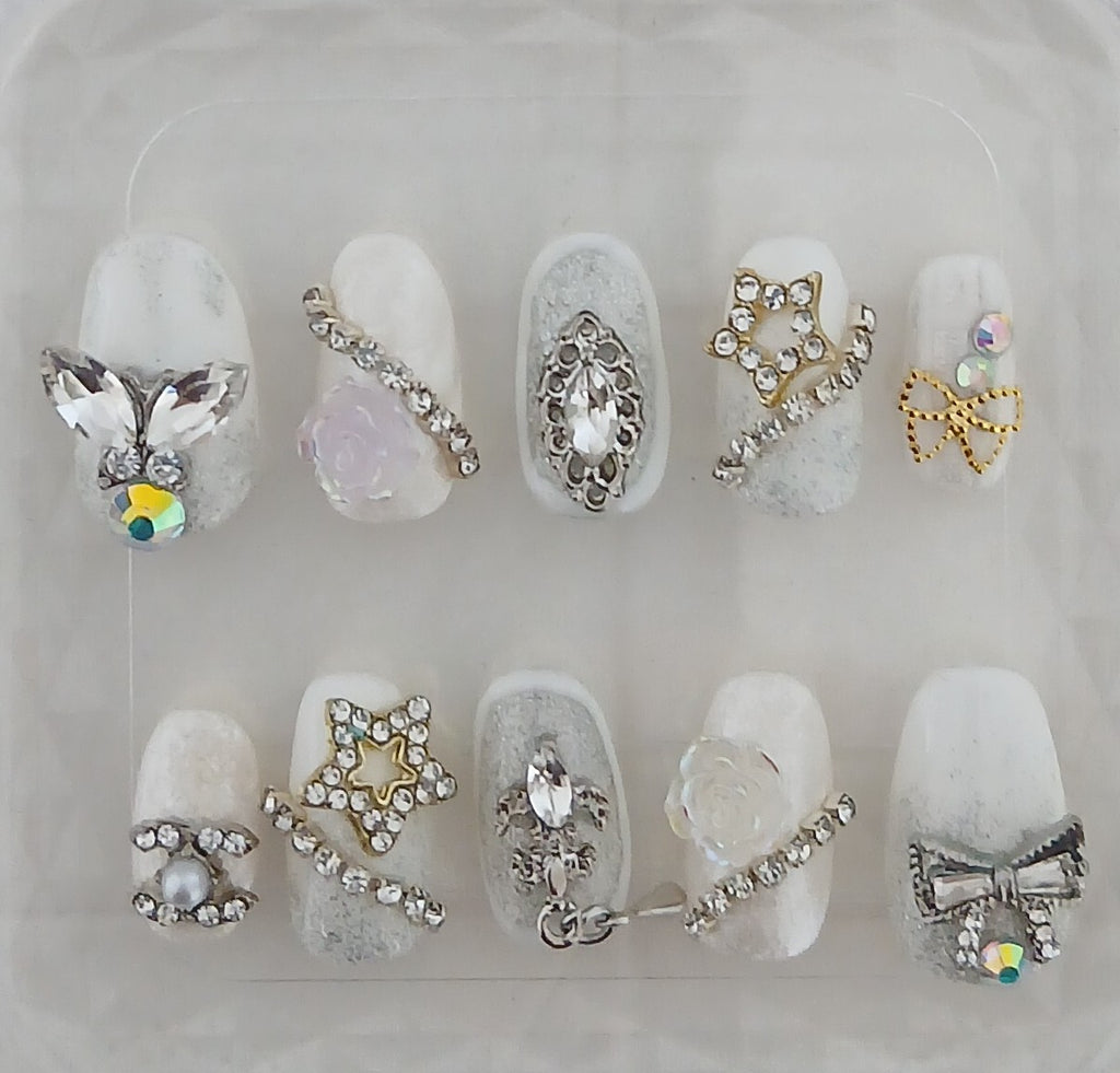 Decorative nail art with various gemstones and embellishments on a clear background