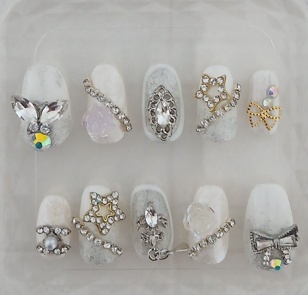 Decorative nail art with various gemstones and embellishments on a clear background