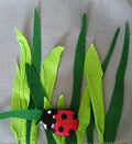 Felt ladybug and grass on a felt background