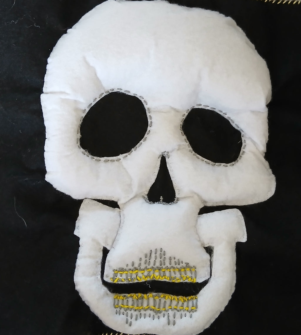 White skull-shaped plush toy with black details on a dark background