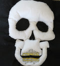 White skull-shaped plush toy with black details on a dark background
