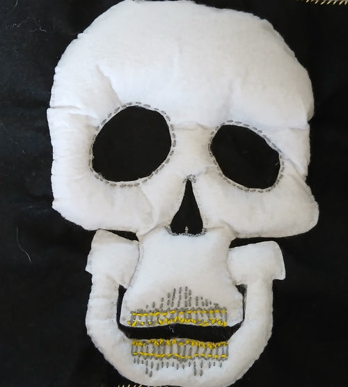 White skull-shaped plush toy with black details on a dark background